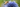 Ein horizontalformatiges Makrofoto einer Honigbiene, die auf der kugelförmigen, blauen Blüte einer Kugeldistel (Echinops) Nektar sammelt. Die Biene ist von der Seite aufgenommen und hat ihren Rüssel in die kleinen Blüten der Distel gesenkt. Der Hintergrund ist unscharf in Grüntönen gehalten.
